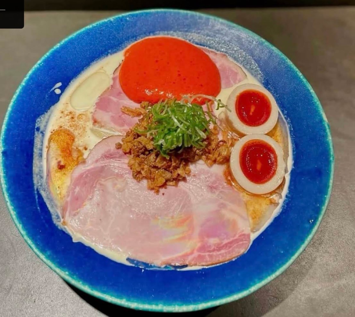 The bowl at Ramen Afro Beats: creamy broth, pink chashu, two eggs and a red paste